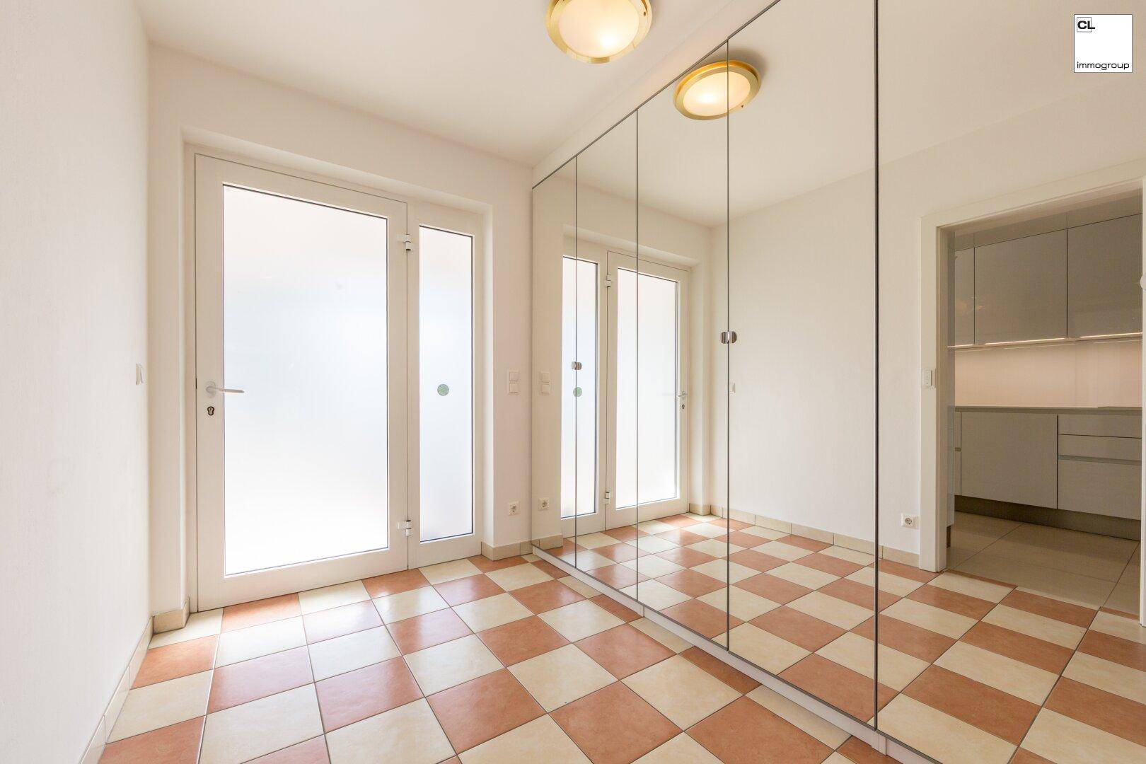 Flur mit großem Spiegelschrank, gemustertem Fliesenboden und Zugang zu weiteren Räumen.