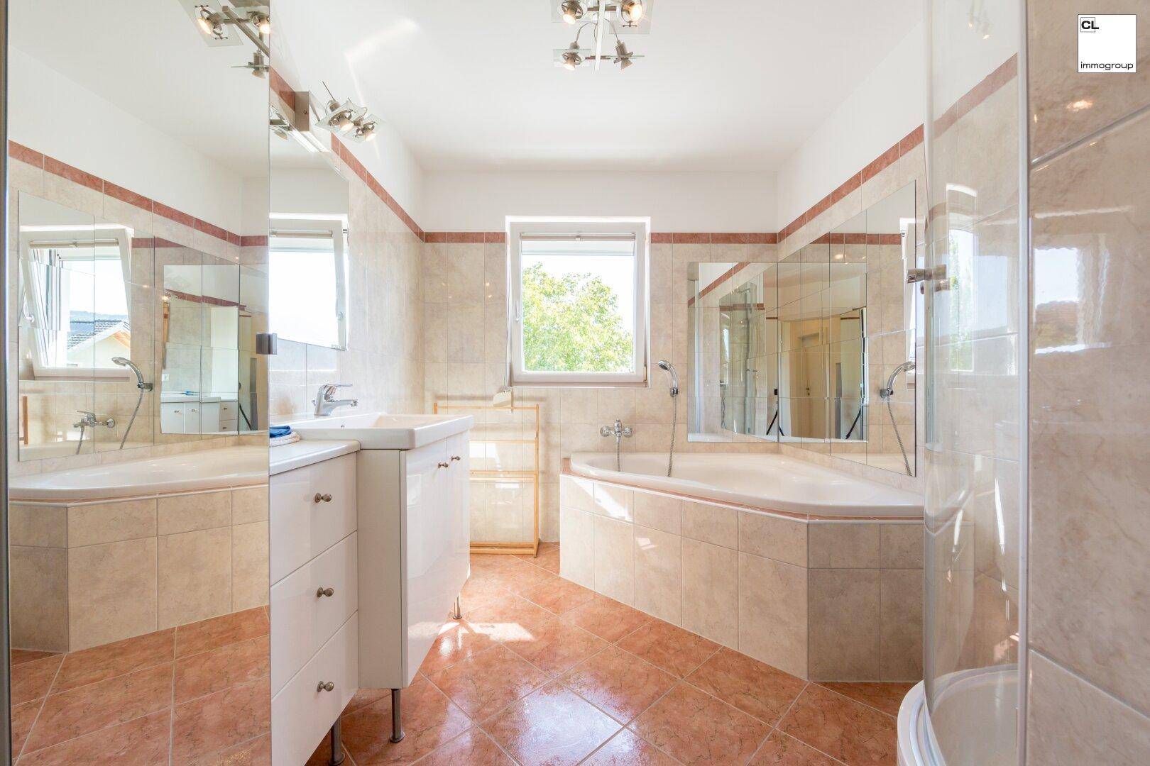 Geräumiges Badezimmer mit Eckbadewanne, Doppelwaschbecken und Fenster für Tageslicht.