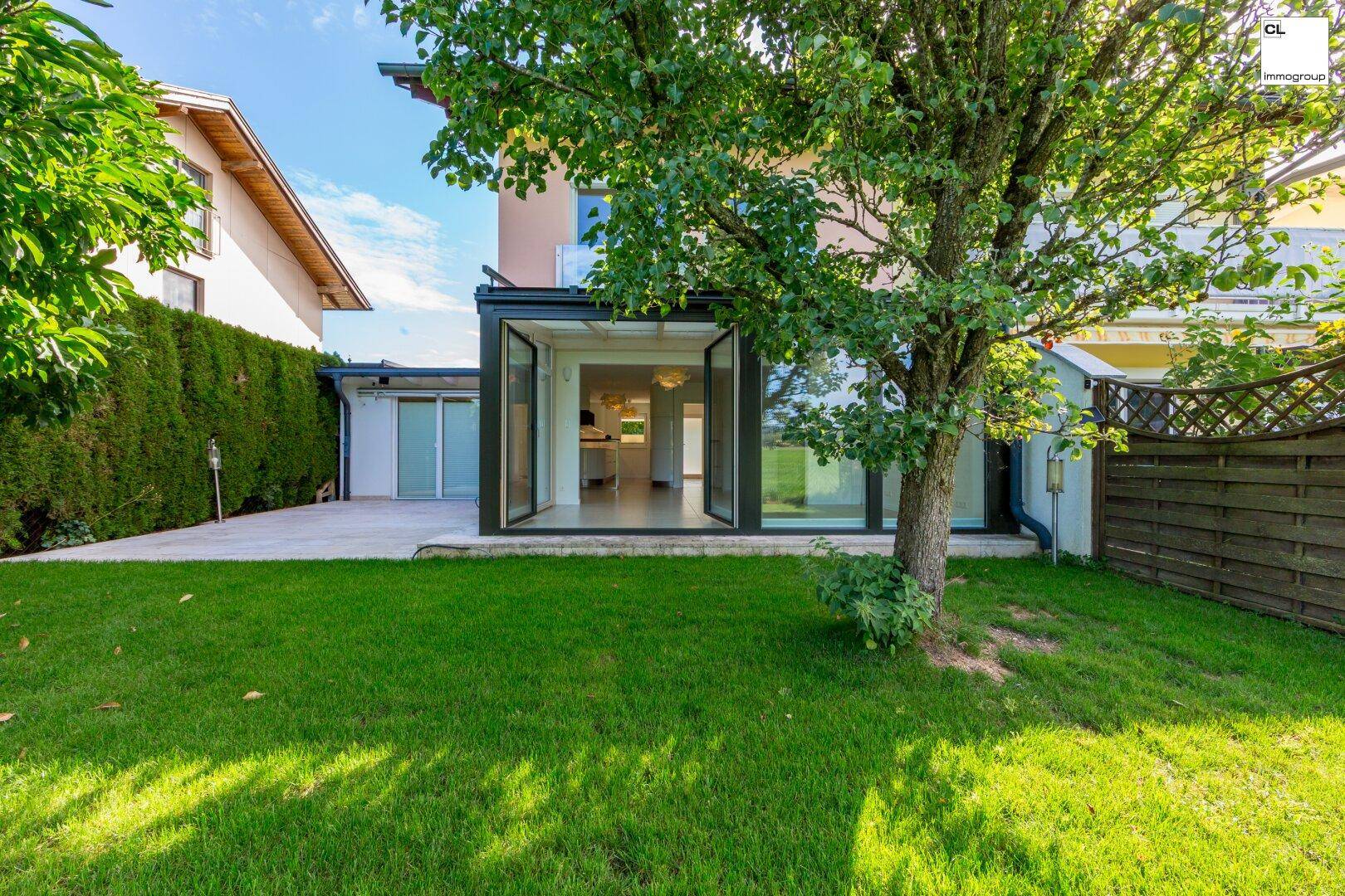 Rückansicht des Hauses mit Wintergarten, Terrasse und gepflegtem Gartenbereich.