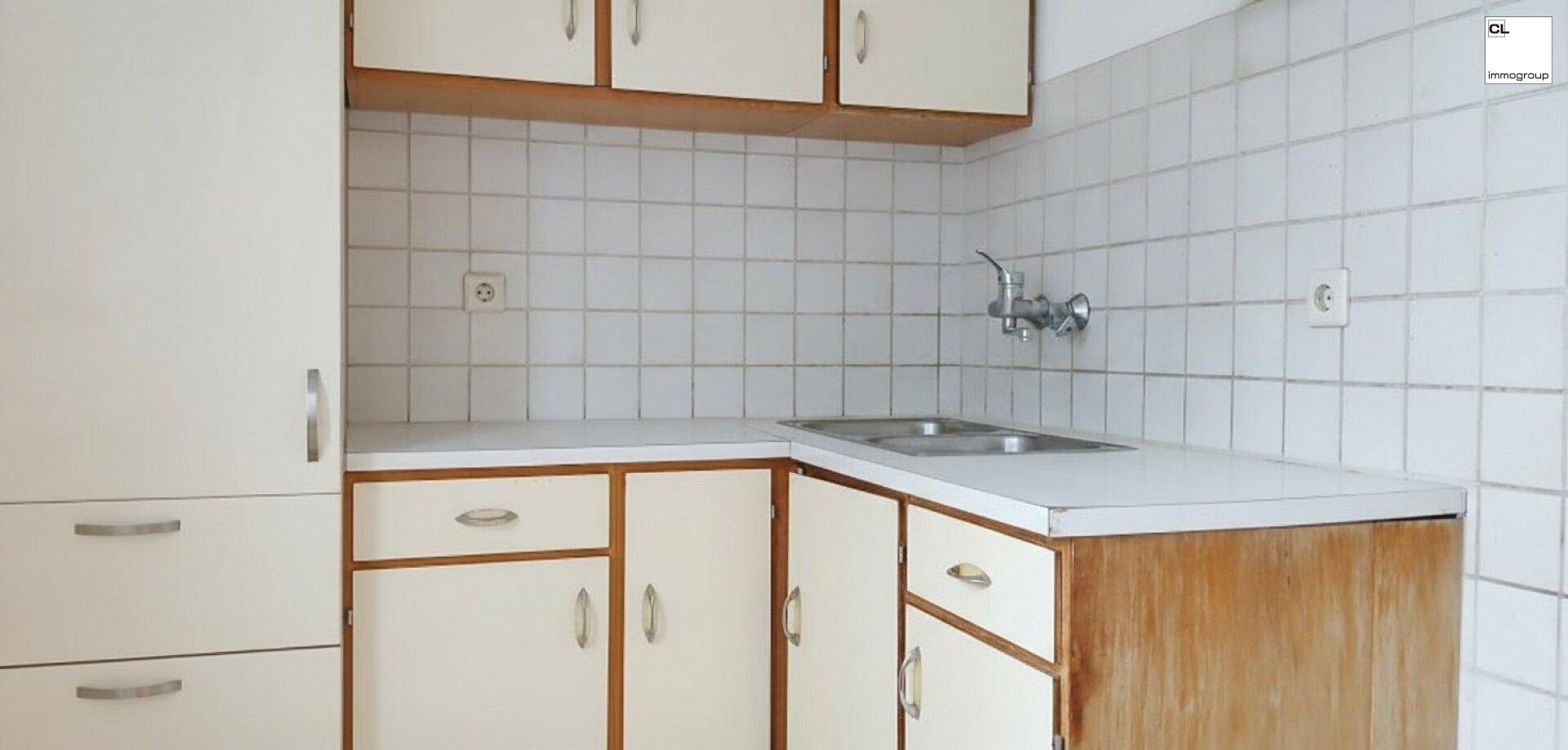 Küche mit älteren Einbauschränken, doppelter Spüle und weiß gefliesten Wänden im traditionellen Stil.