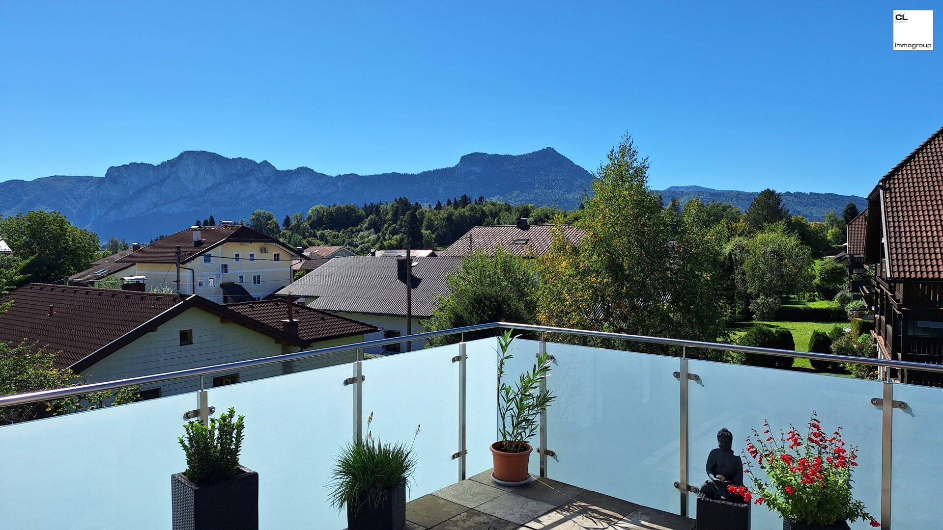 Terrasse mit Glasgeländer und Panoramablick auf die umliegende Berglandschaft und Dächer.