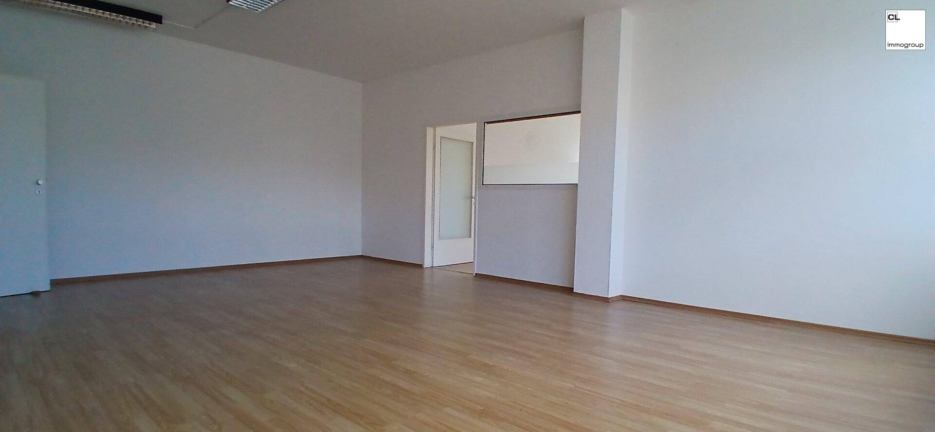 Geräumiger Bürobereich mit Holzboden und Zugang zu einem weiteren Raum, ideal für flexible Arbeitsplatzgestaltung.