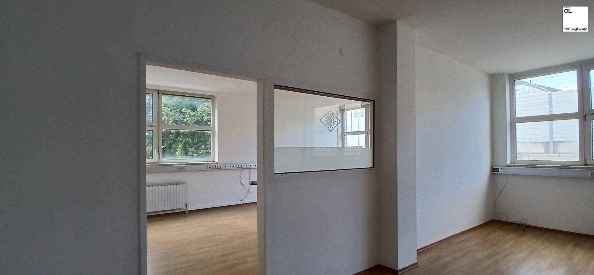 Blick von einem Büroraum in einen angrenzenden Bereich mit Fenstern, der eine offene Gestaltung ermöglicht.