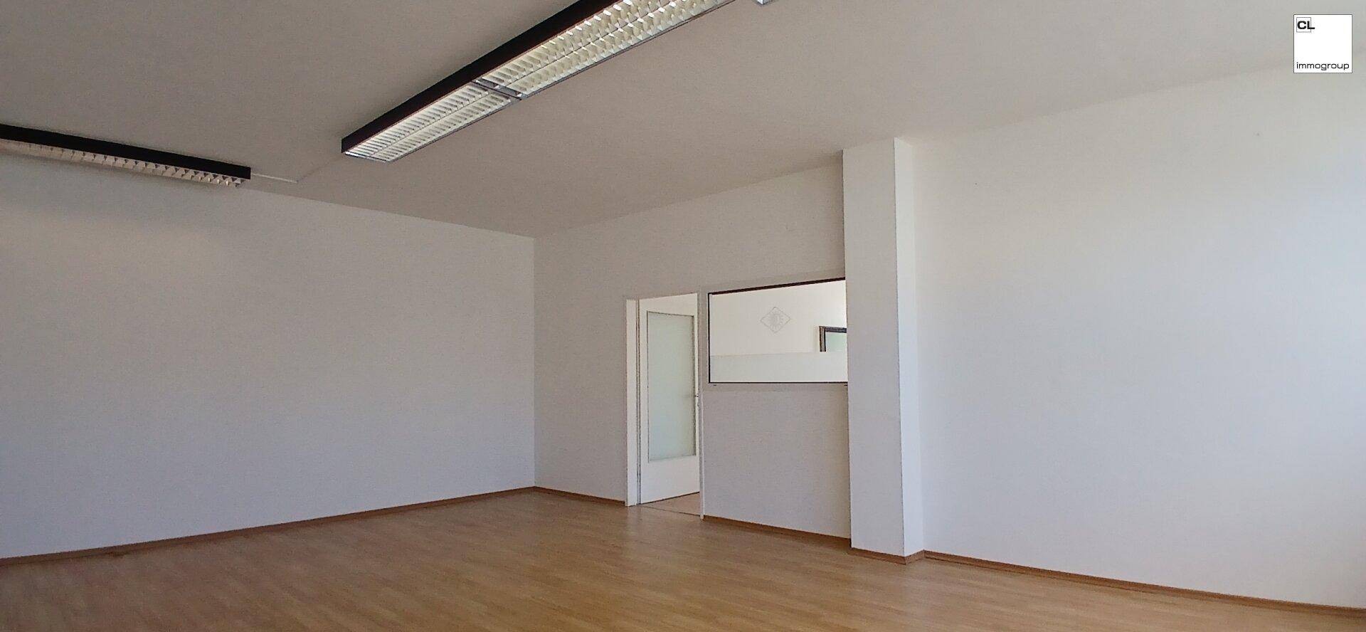 Leerer Bürobereich mit Holzboden und Zugang zu einem Nebenraum, ideal für eine flexible Nutzung.