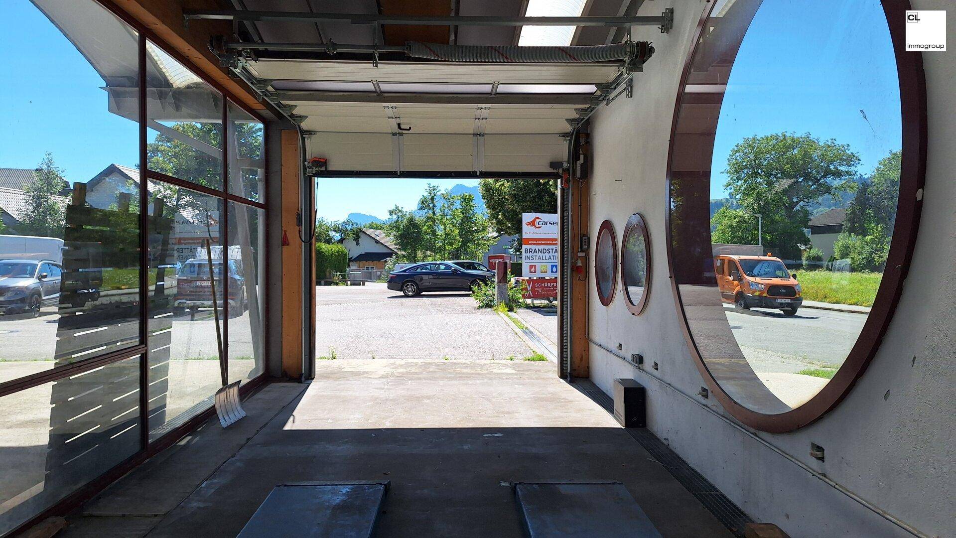 Innenansicht einer Garage mit offenem Tor, Blick auf den Außenbereich und die umliegende Landschaft.