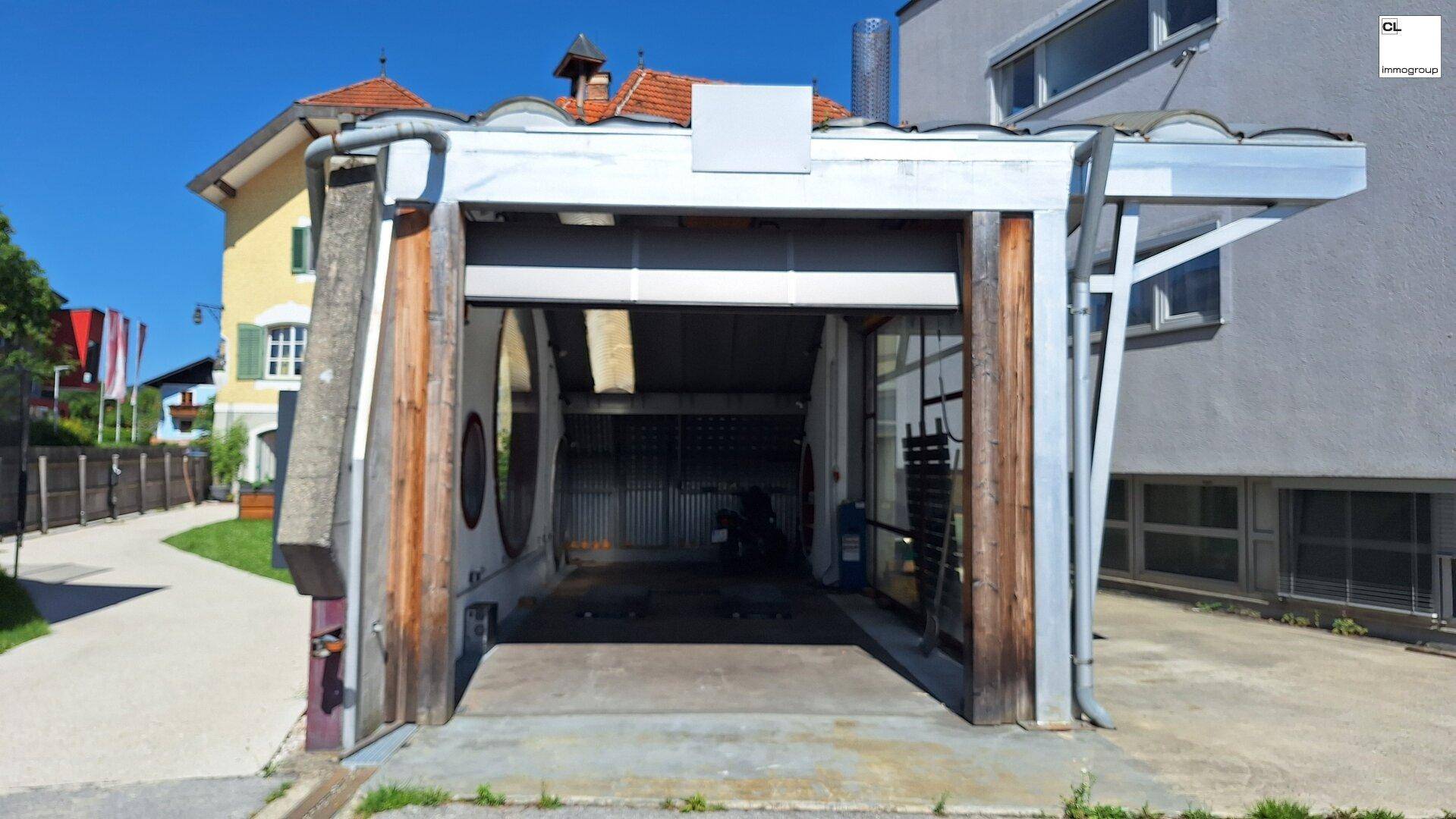 Offener Eingangsbereich einer modernen Garage oder Werkstatt mit Rolltor und Blick ins Innere.