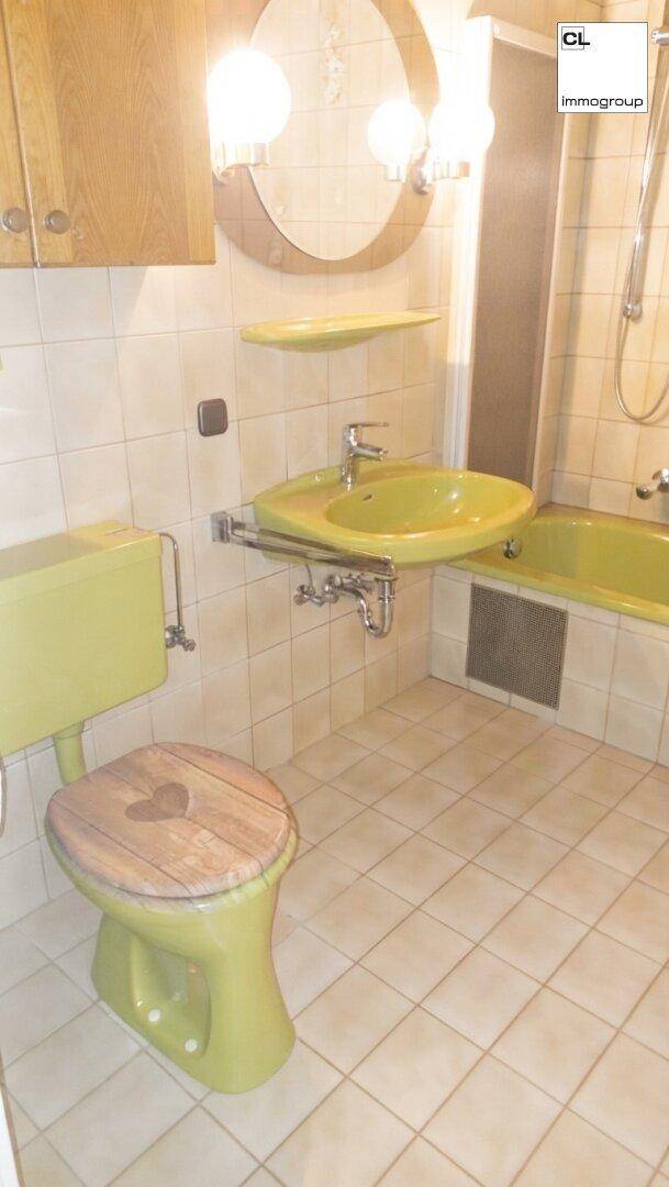 Badezimmer im Stil der 80er Jahre mit gelben Sanitärobjekten, Fliesen und einer Badewanne.