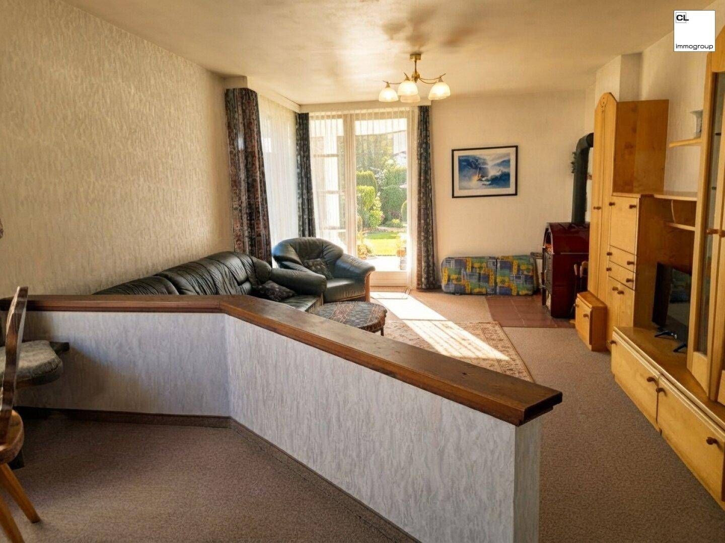 Geräumiges Wohnzimmer mit Teppichboden, Ledersofa und direktem Zugang zum Garten.