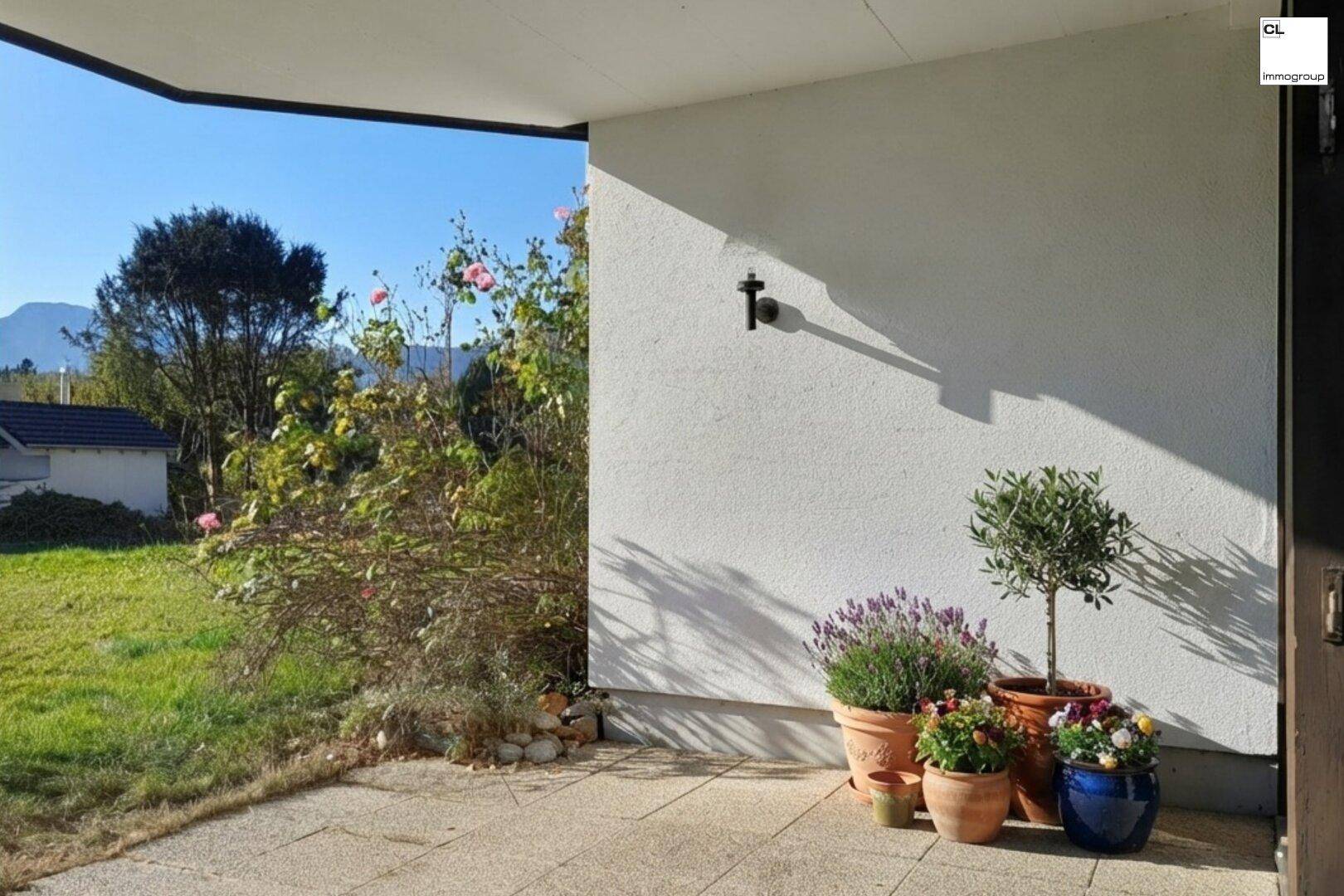 Sonniger Terrassenbereich mit Topfpflanzen und weitem Blick auf die umliegende Landschaft und Berge.
