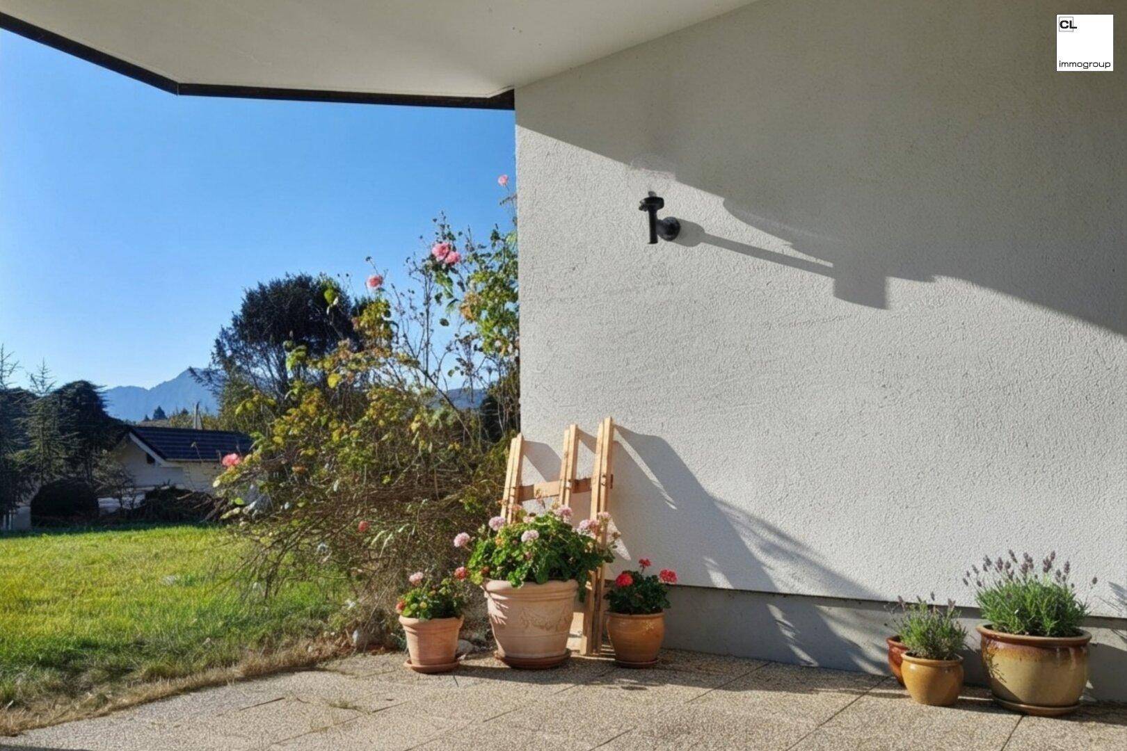 Sonniger Terrassenbereich mit Topfpflanzen und weitem Blick auf die umliegende Landschaft und Berge.