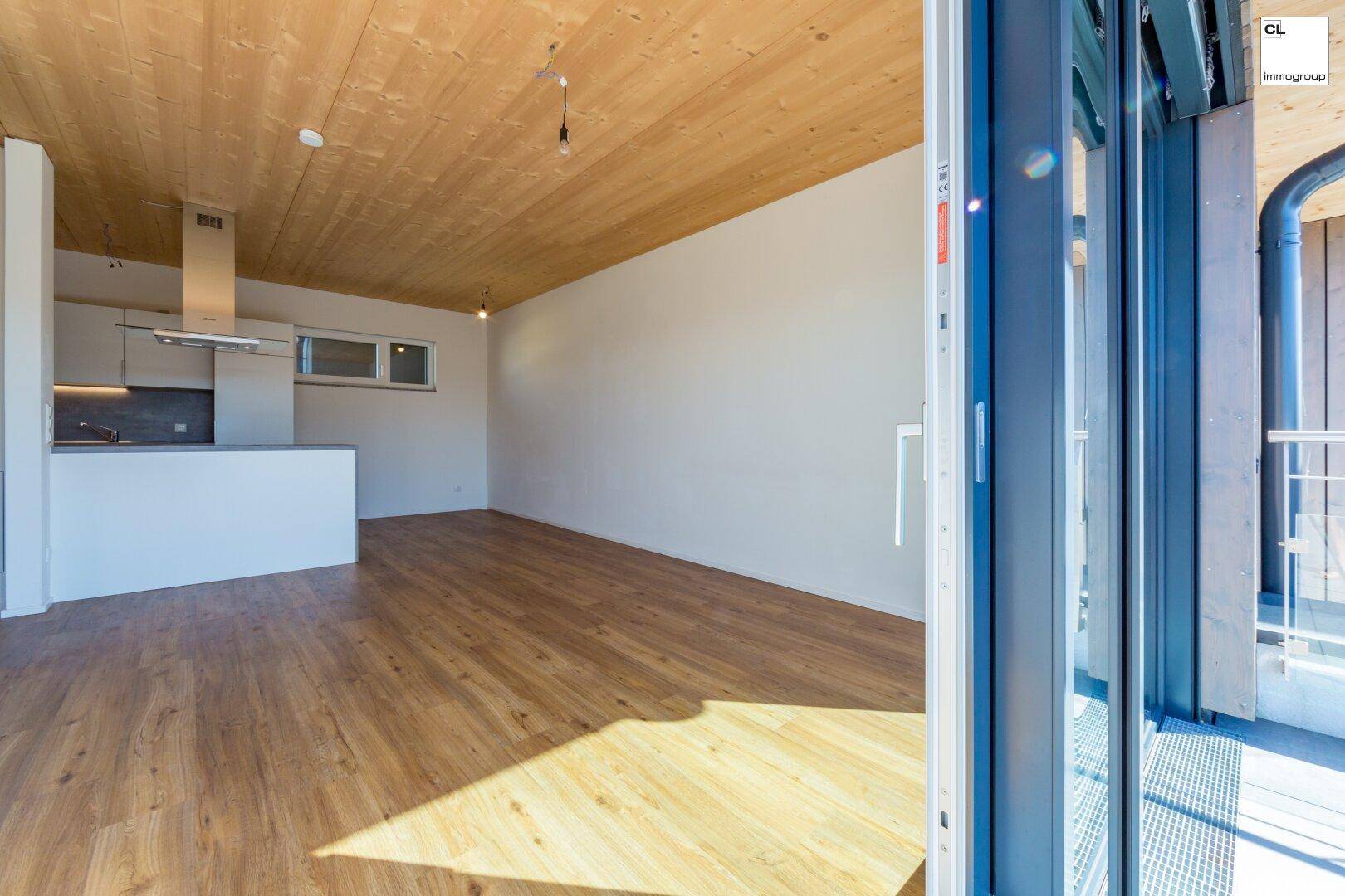 Heller, offener Wohn- und Essbereich mit Holzboden und moderner Holzdecke.