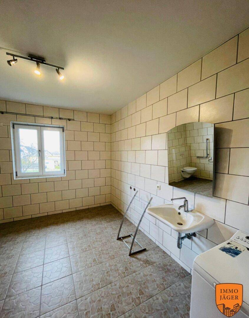 Helles Badezimmer mit weißen Fliesen, Waschbecken und Fenster, bereit zur Fertigstellung.