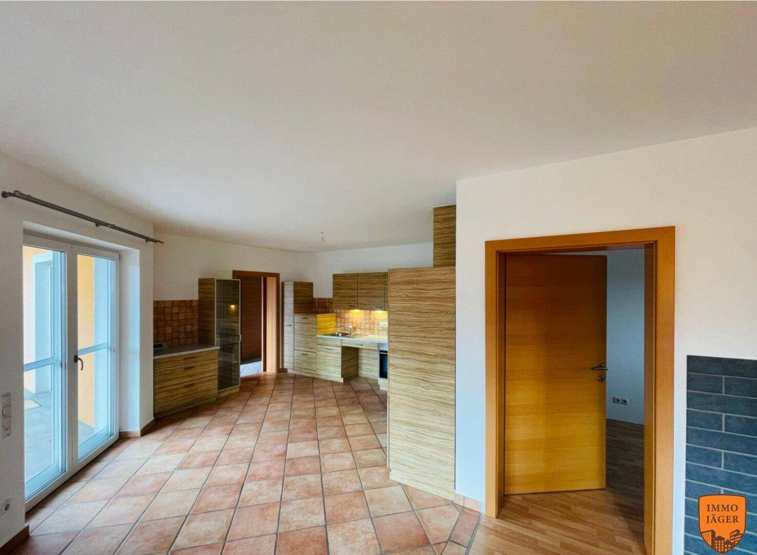 Offene Küche mit Terrakotta-Fliesenboden und Zugang zu einem weiteren Raum und der Terrasse.