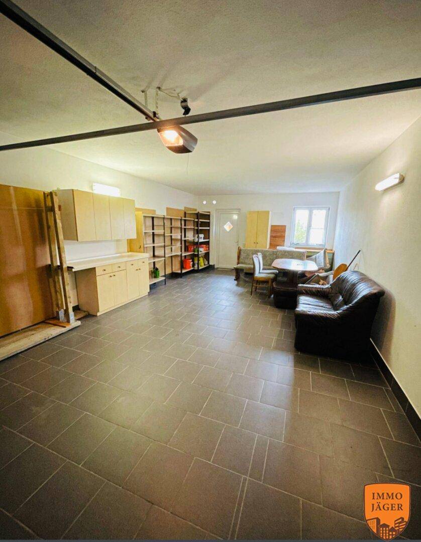 Großer Mehrzweckraum im Untergeschoss mit Fliesenboden, Sitzgelegenheiten und Stauraum.