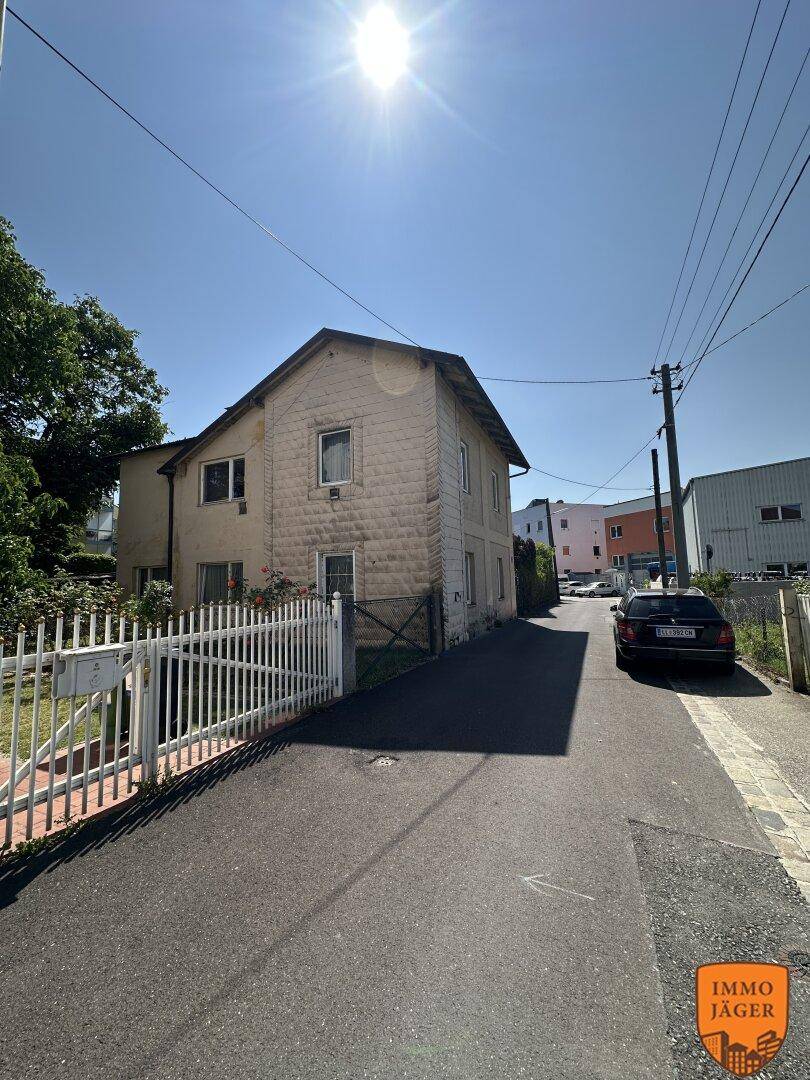 Außenansicht eines Hauses mit Steinfassade und kleinem Vorgarten an einem sonnigen Tag.