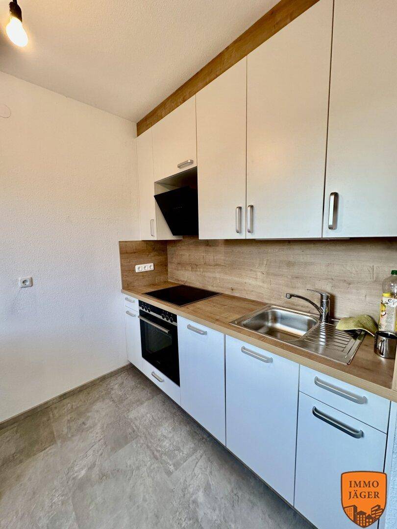 Moderne Einbauküche mit weißen Schränken, Holzoptik-Arbeitsplatte und integrierten Geräten.