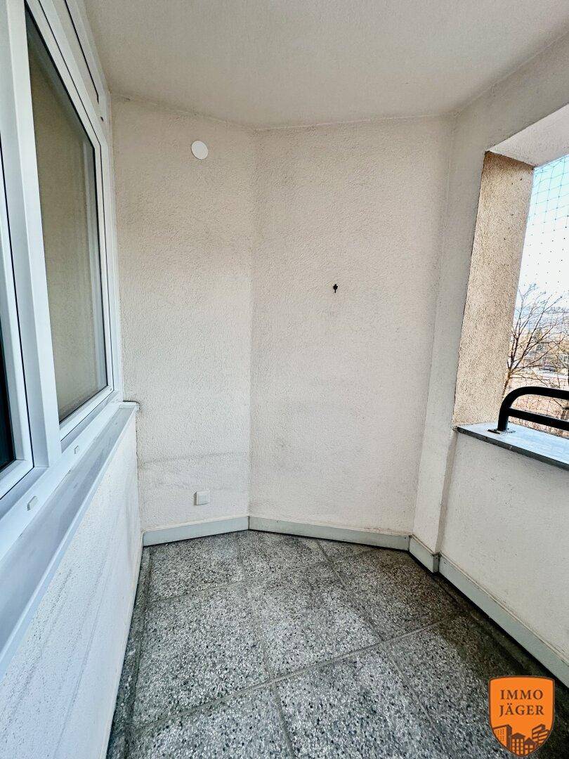 Überdachter Balkon mit Fliesenboden und Blick ins Grüne, ideal für entspannte Stunden.