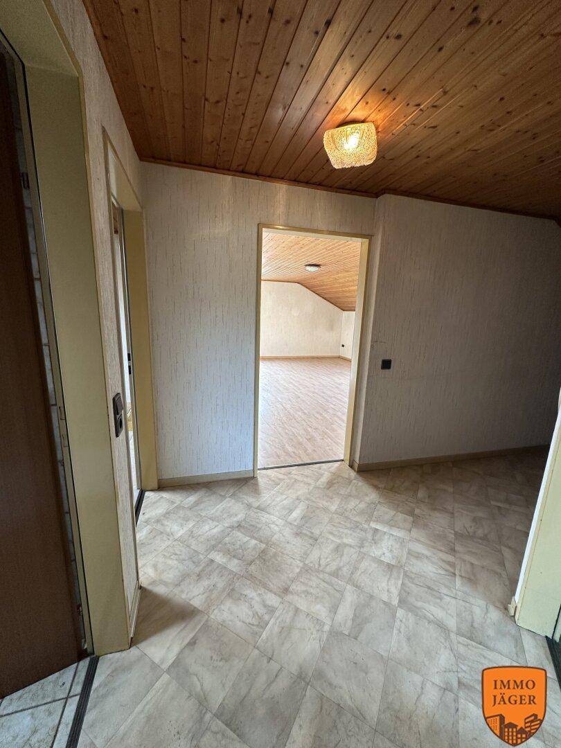Flur im Dachgeschoss mit gemustertem Fliesenboden, Holzdecke und Zugang zu weiteren Räumen.