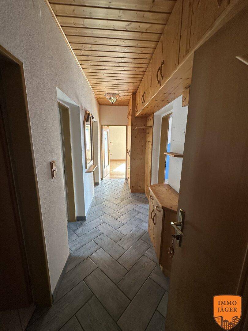 Rustikaler Flur mit Holzvertäfelung an Decke und Wänden, sowie einem Fischgrätmuster-Fliesenboden.
