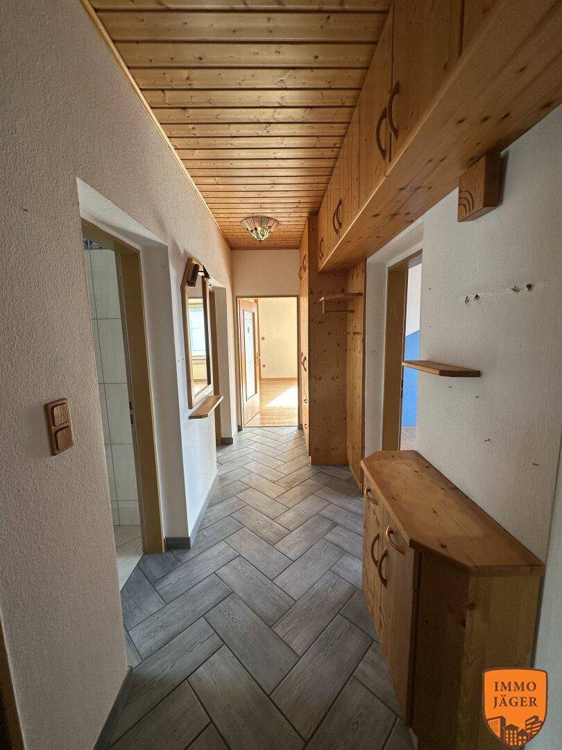 Rustikaler Flur mit Holzvertäfelung an Decke und Wänden, sowie einem Fischgrätmuster-Fliesenboden.