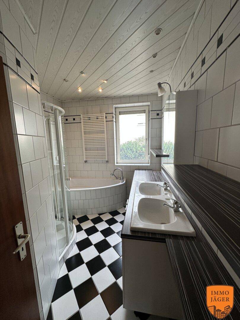 Badezimmer mit schwarz-weiß kariertem Fliesenboden, Doppelwaschbecken, Badewanne und Duschkabine.