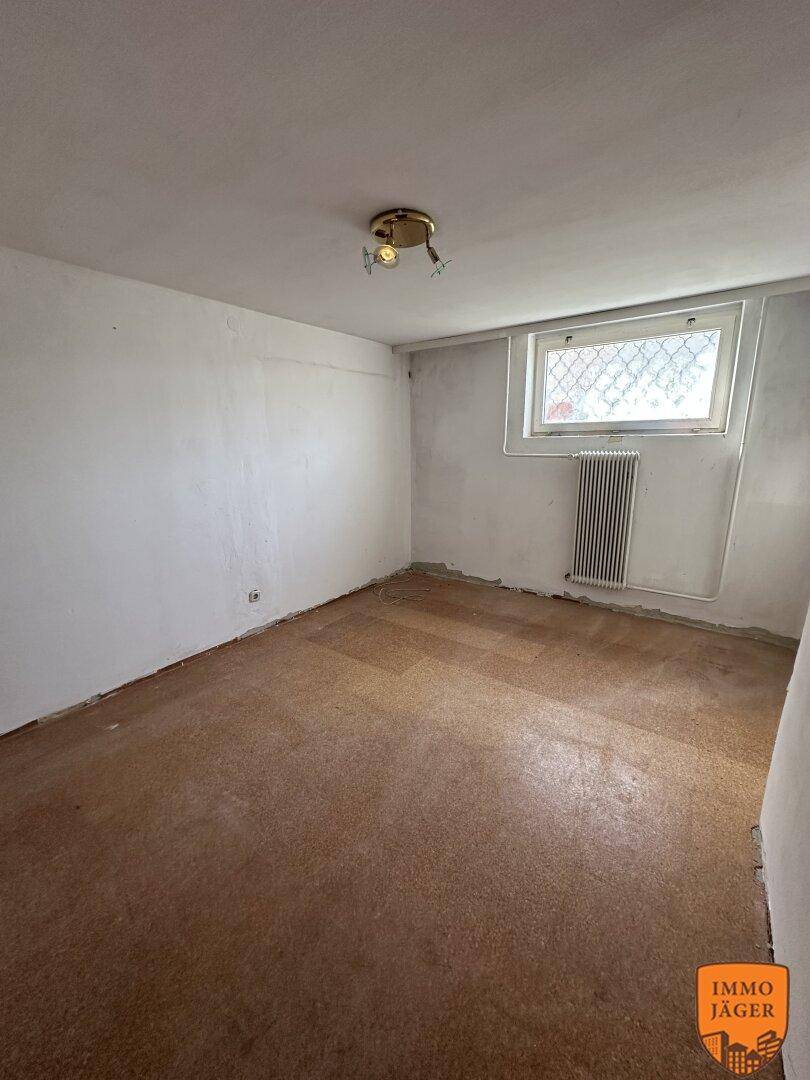 Kellerraum mit Linoleumboden und einem Fenster, das für Belüftung und etwas Tageslicht sorgt.