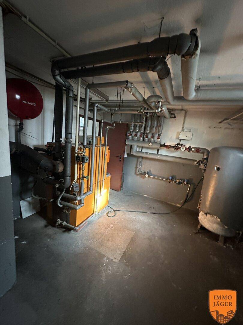 Heizungsraum mit umfangreicher Verrohrung und Heizkessel im Kellerbereich des Gebäudes.