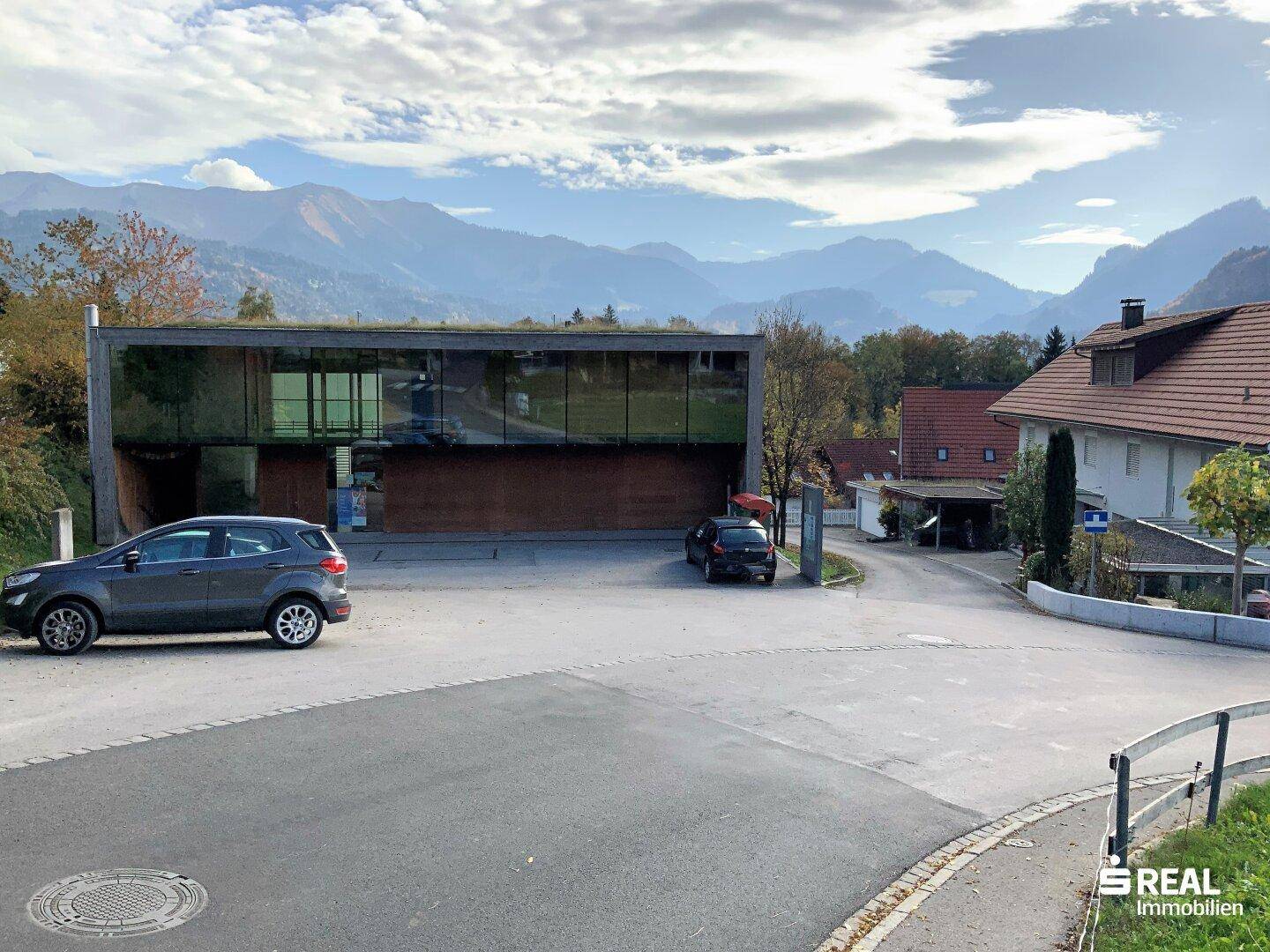 Moderne Architektur mit großen Glasflächen und Blick auf die umliegende Bergwelt.