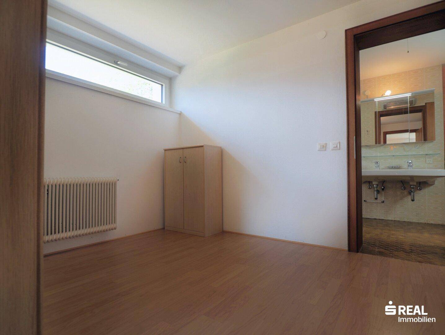 Schlafzimmer mit hellem Holzboden und direktem Zugang zu einem Badezimmer.