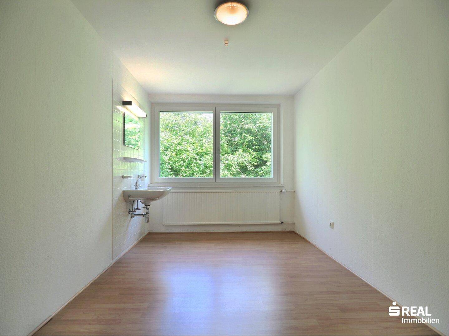 Raum mit Waschbecken, Fenster und hellem Holzboden, ideal als Hauswirtschaftsraum nutzbar.