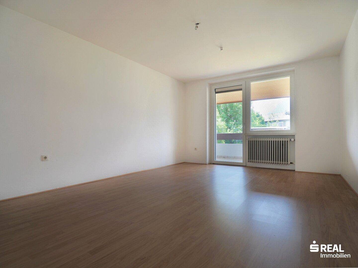 Helles Schlafzimmer mit hellem Holzboden und Zugang zu einem Balkon oder einer Terrasse.