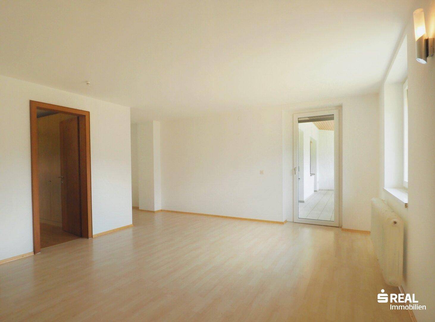 Heller Flur mit hellem Holzboden und Zugang zu weiteren Räumen sowie einem Balkon.