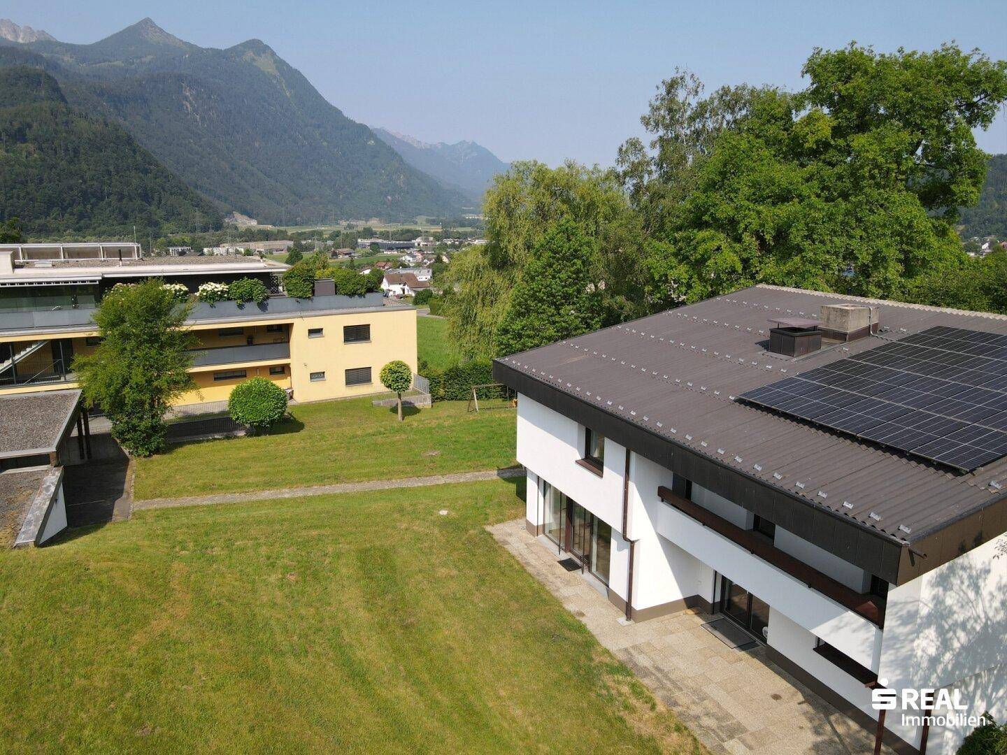 Luftaufnahme des Hauses mit Photovoltaikanlage und weitem Blick auf die Berglandschaft.