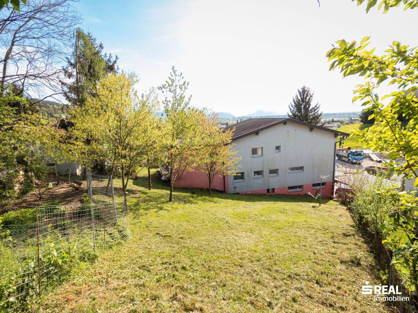 Großzügige Rasenfläche vor einem Wohnhaus mit Blick auf die umliegende Landschaft.
