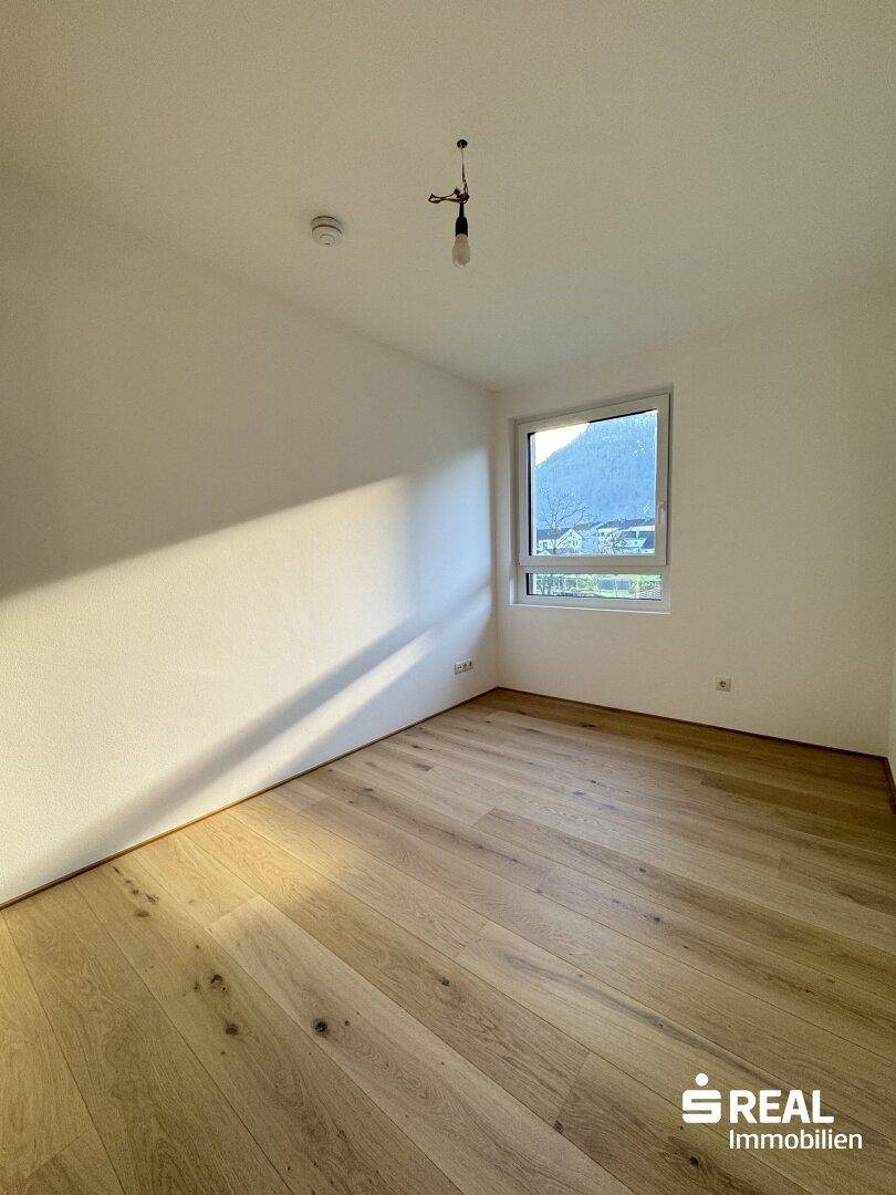 Sonniger Raum mit Holzparkettboden und Fenster, das viel natürliches Licht hereinlässt.