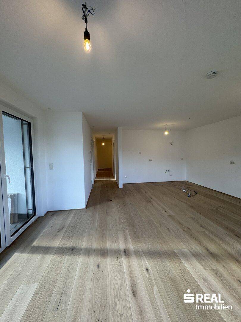 Geräumiger Wohnbereich mit Holzparkettboden und hellem Ambiente.