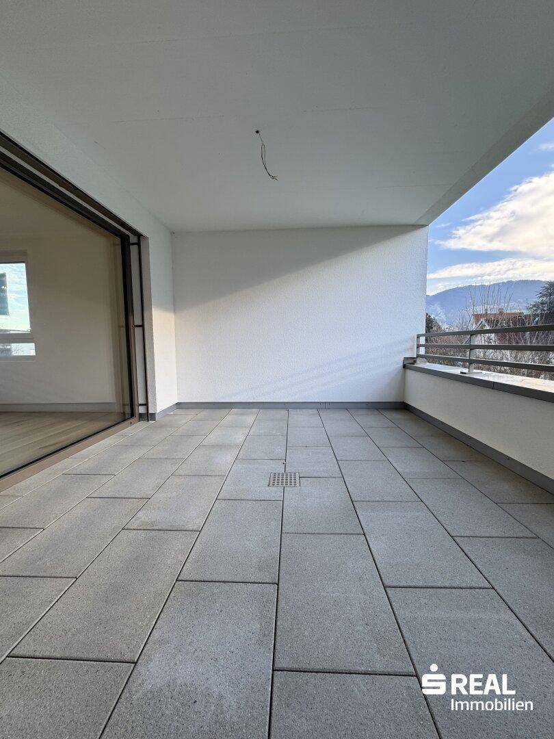 Großer Balkon mit Fliesenboden und Blick auf die umliegende Landschaft.