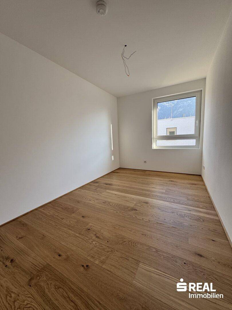 Geräumiges Schlafzimmer mit Holzboden, weißen Wänden und einem Fenster mit Bergblick.