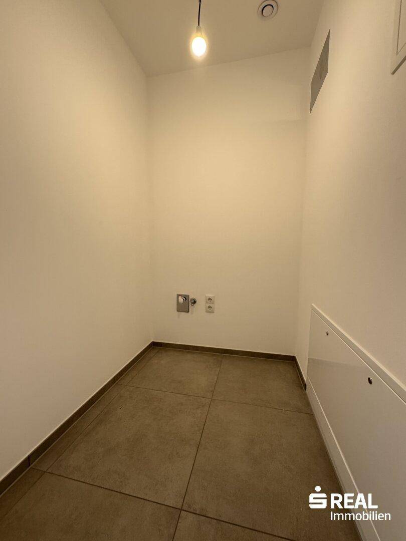 Praktischer Hauswirtschaftsraum mit Fliesenboden und Anschlüssen für Waschmaschine und Trockner.