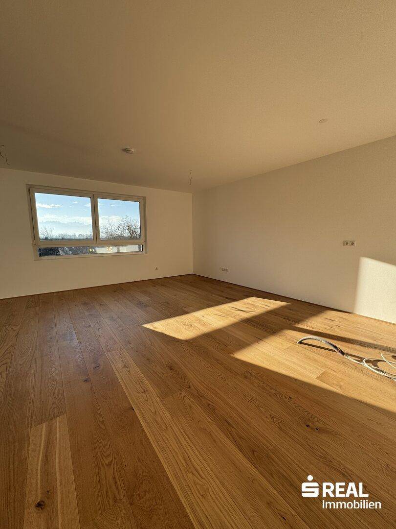 Lichtdurchfluteter Wohnraum mit neuem Holzboden und weitem Blick ins Grüne.