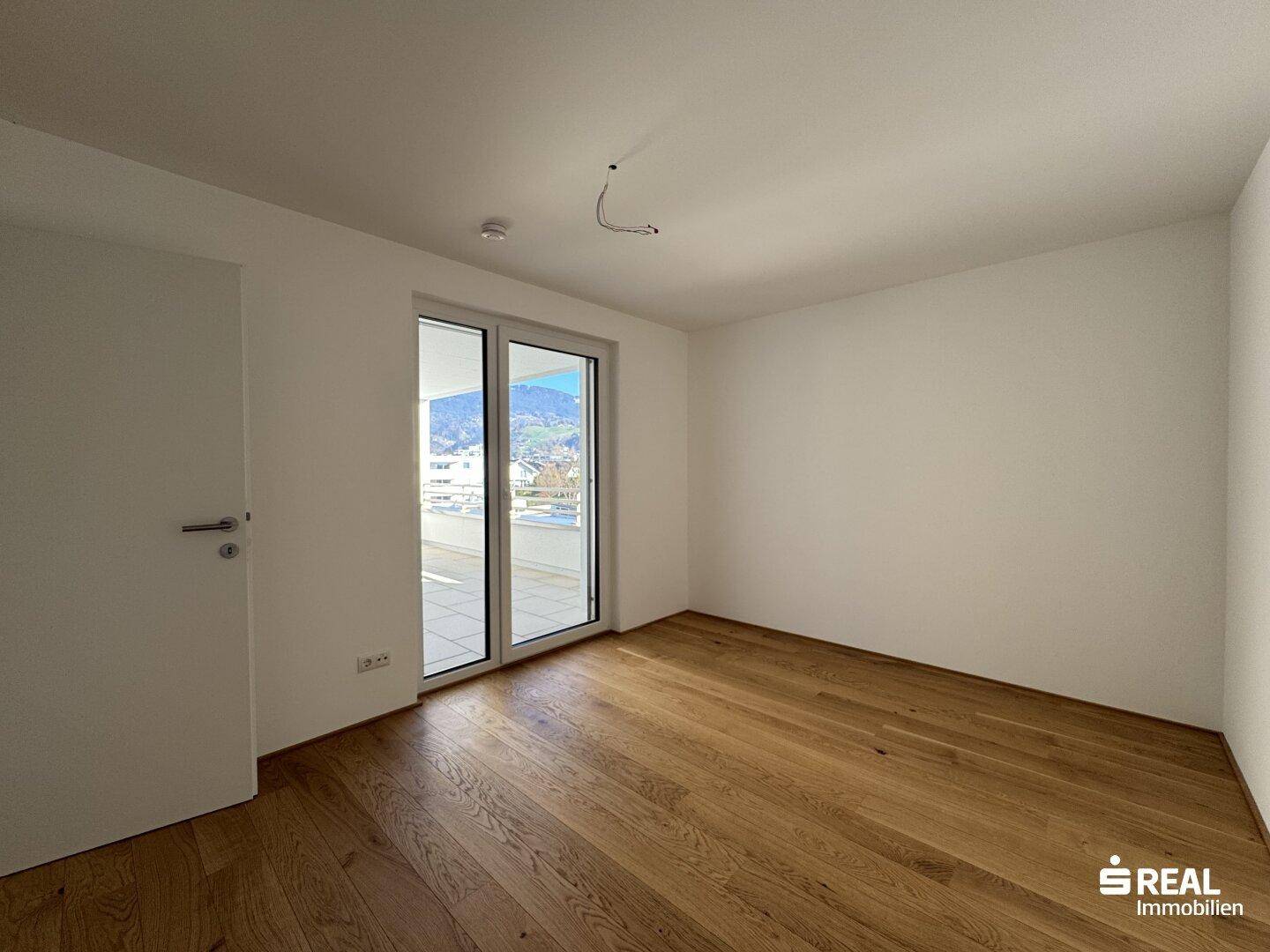 Geräumiges Zimmer mit Holzparkett und Zugang zu einem Balkon, ideal als Schlaf- oder Arbeitszimmer.