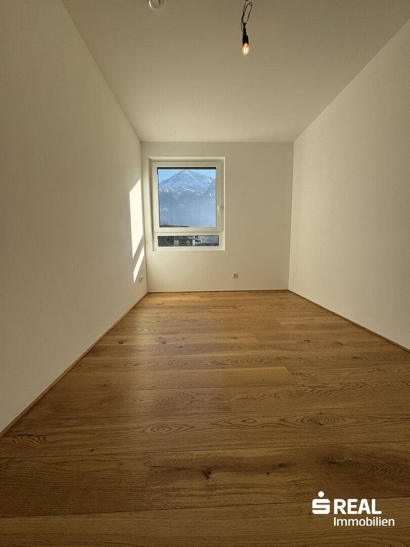 Helles Zimmer mit Eichenparkett und einem Fenster, das einen schönen Blick auf die Berge bietet.