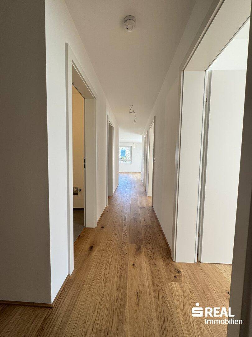 Langer, heller Flur mit elegantem Holzparkett, der die verschiedenen Wohnbereiche miteinander verbindet.