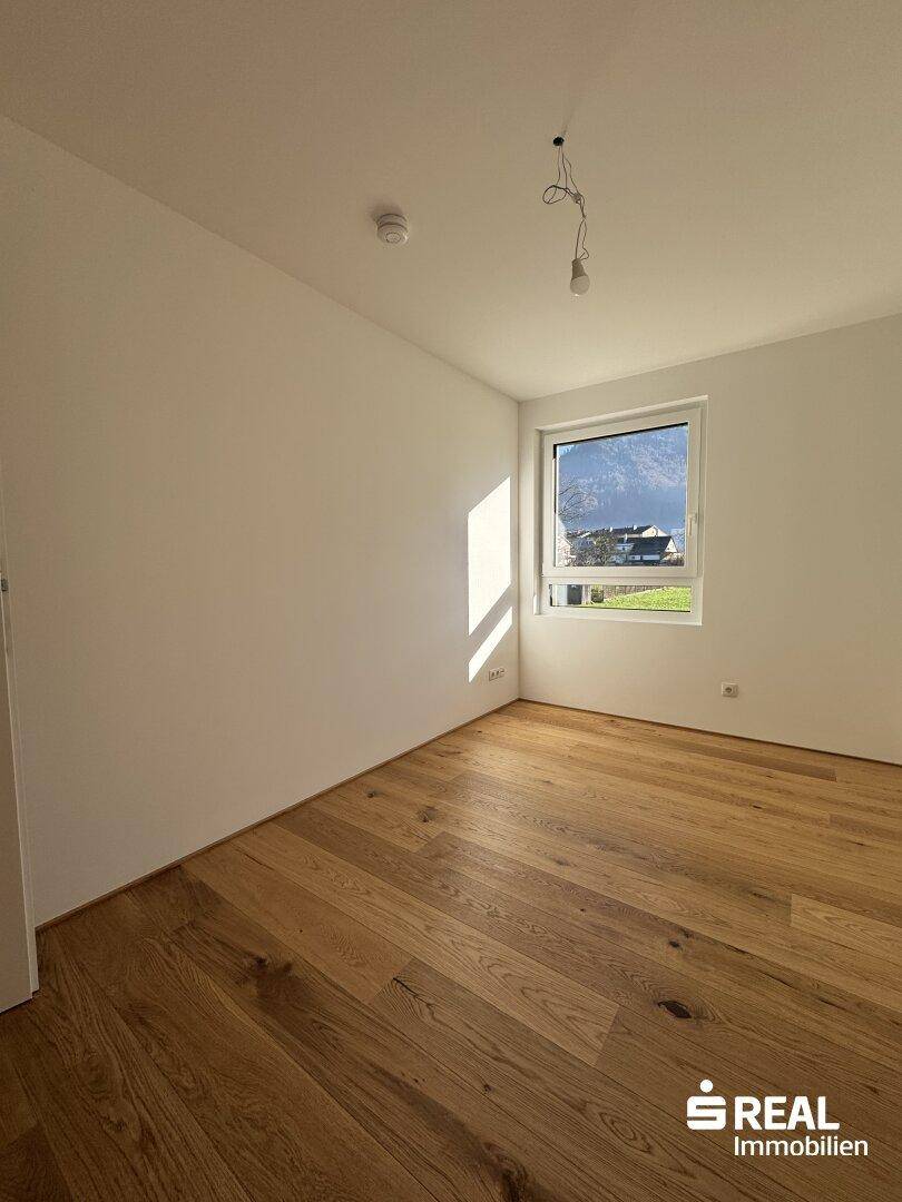 Helles Zimmer mit schönem Holzparkett und einem Fenster, das viel Tageslicht und Bergblick bietet.