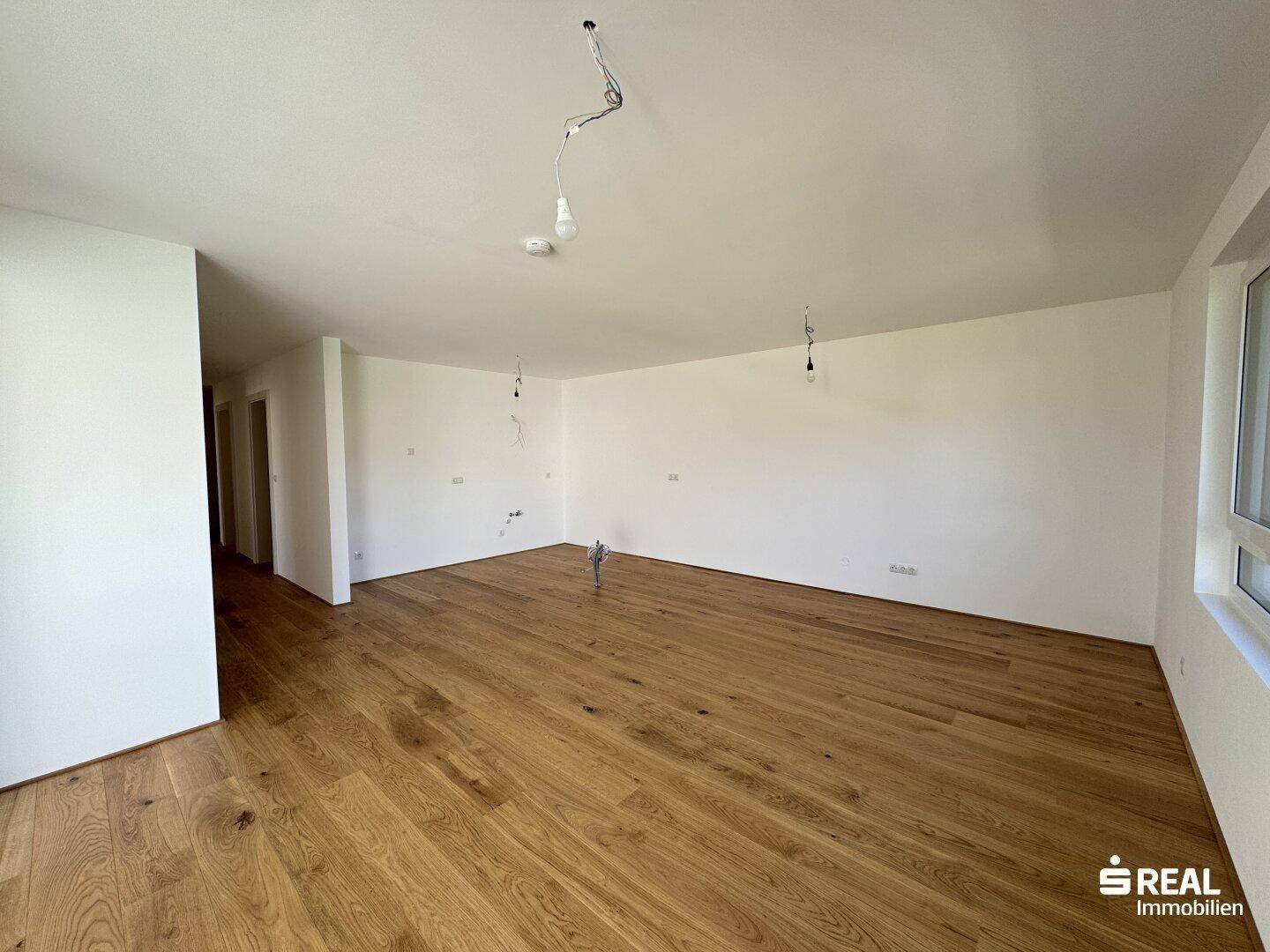 Heller und geräumiger Wohnbereich mit elegantem Holzparkett, ideal für komfortables Wohnen.