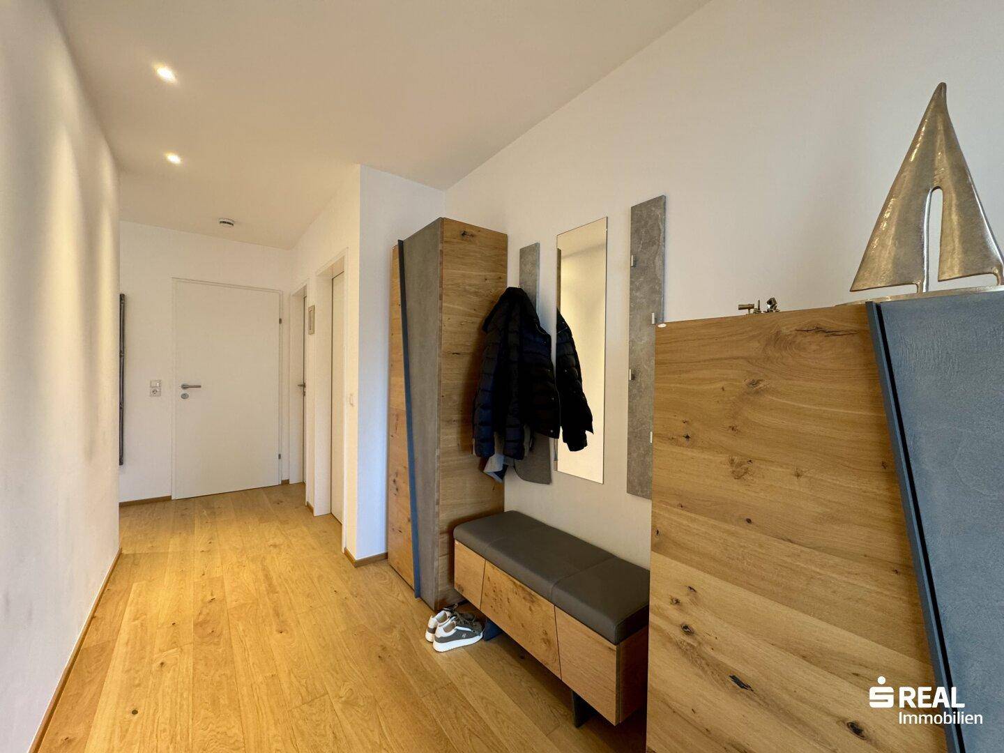 Heller Eingangsbereich mit Holzboden, Garderobe und modernen Holzmöbeln.