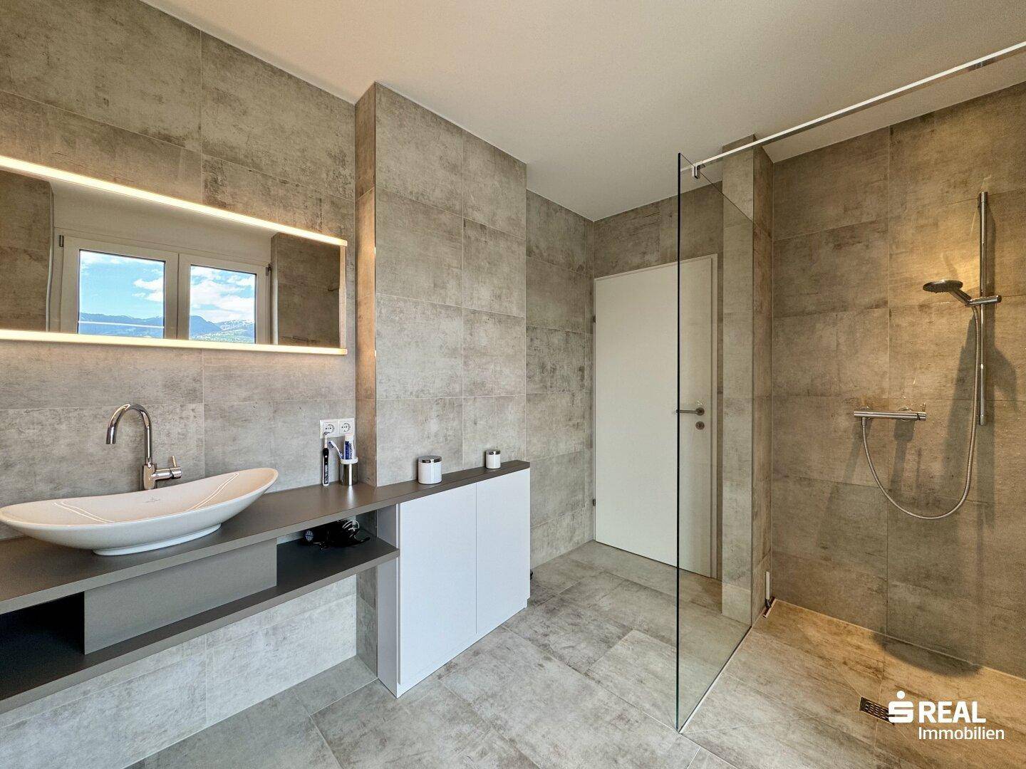 Geräumiges Badezimmer mit begehbarer Dusche, modernem Waschtisch und Fensterblick.