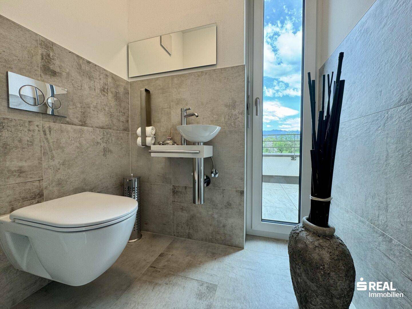 Modernes Gäste-WC mit Wand-WC, kleinem Waschbecken und Fenster mit Ausblick.