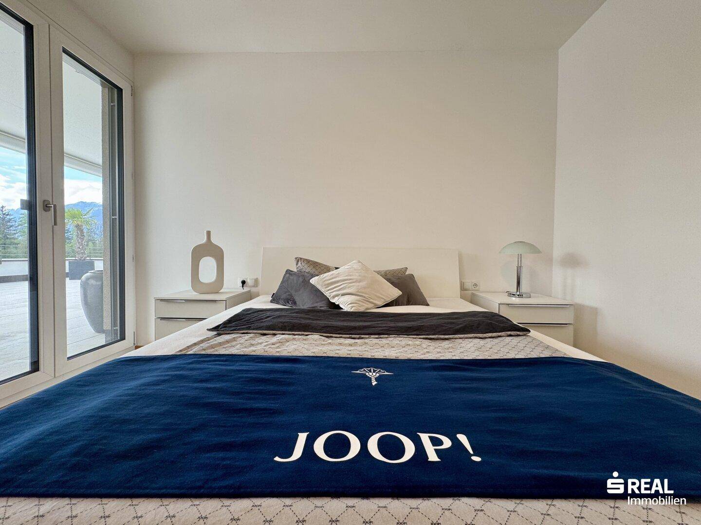 Gemütliches Schlafzimmer mit modernem Bett und direktem Zugang zur sonnigen Dachterrasse.