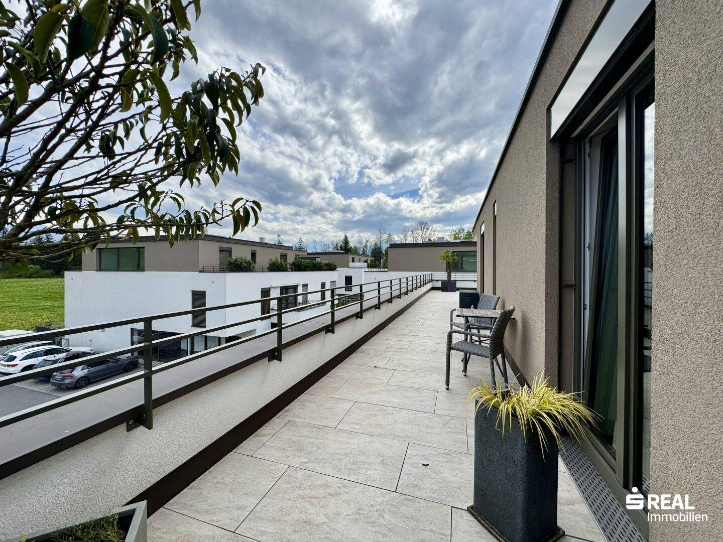 Seitlicher Terrassenbereich mit Blick auf den Parkplatz und die umliegende Bebauung.